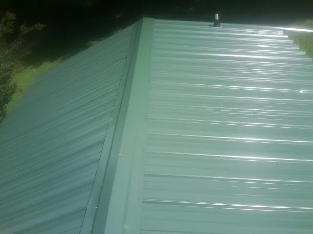 New green metal panels meeting at the ridge of a roof — Flat Roof Repair work by our crew in Kent